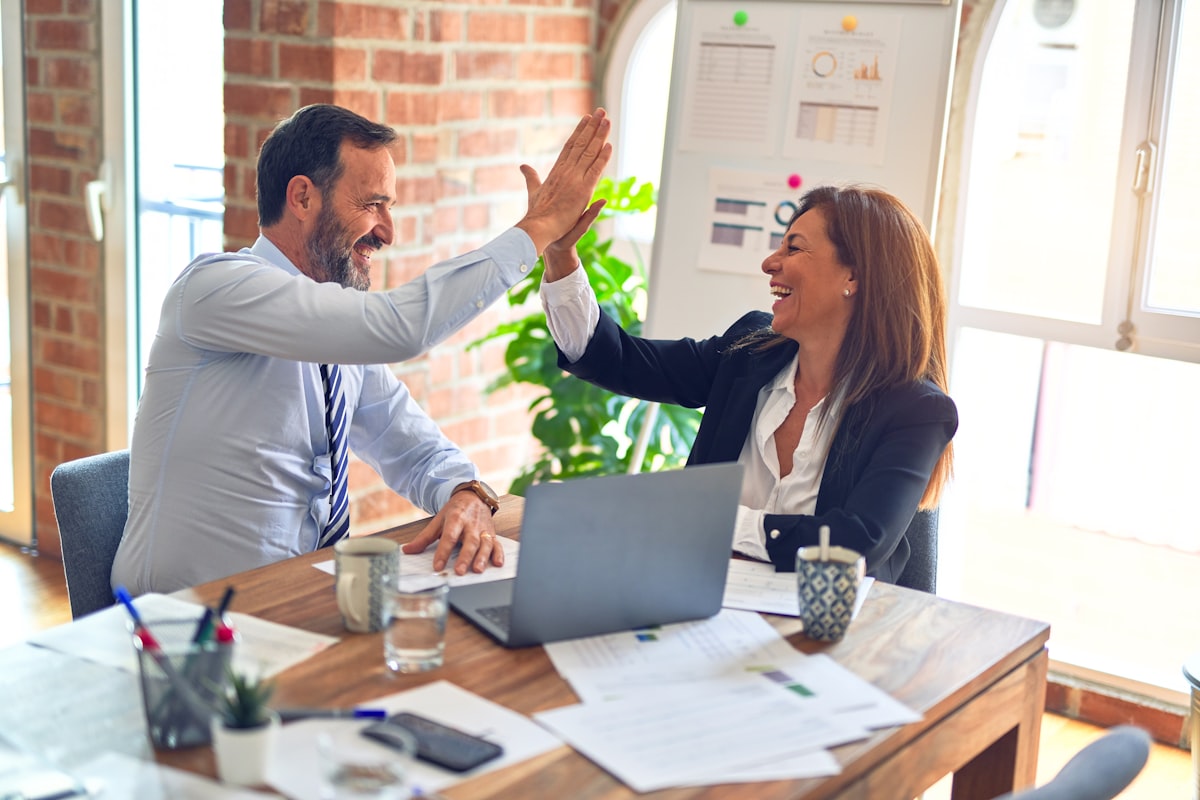 Two colleagues celebrating in their office after finishing their compliance paperwork